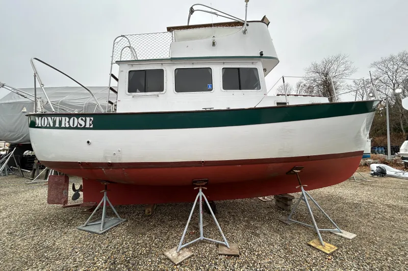 The Image of 1973 Willard 30 boat "Montrose" on stands, white and green hull, outdoor storage. - 0