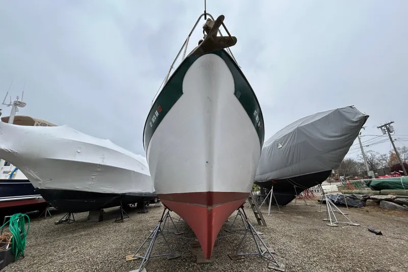 Slide: The Image of 1973 Willard 30 boat on stands, flanked by covered vessels, overcast sky. - 20