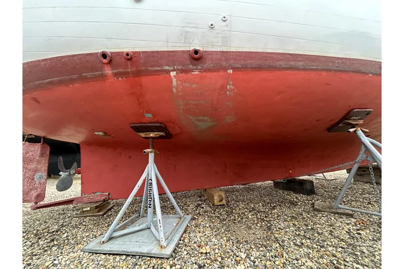 Slide: The Image of Bottom view of a 1973 Willard 30 boat on stands, showing red hull and propeller. - 23