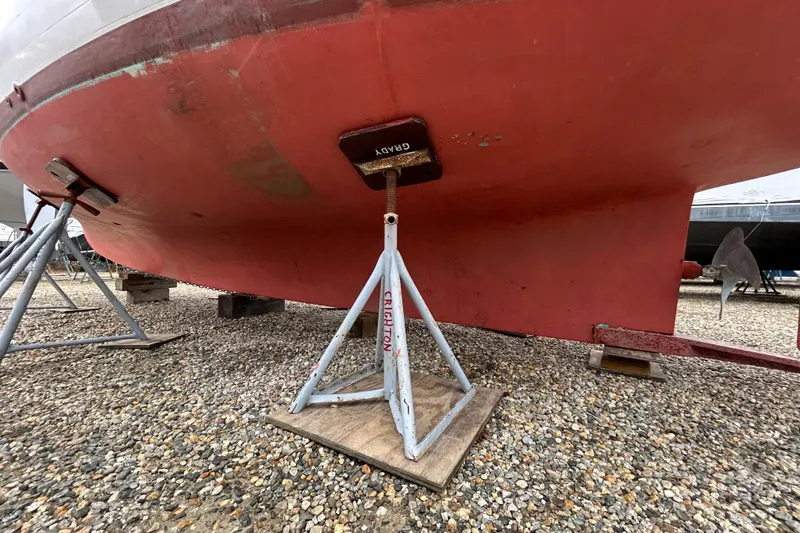 Slide: The Image of 1973 Willard 30 boat hull supported by stands on gravel surface. - 27