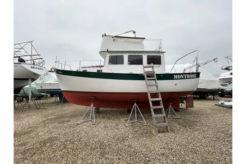 Slide: The Image of 1973 Willard 30 boat "Montrose" on stands, with ladder access, in a gravel yard. - 3