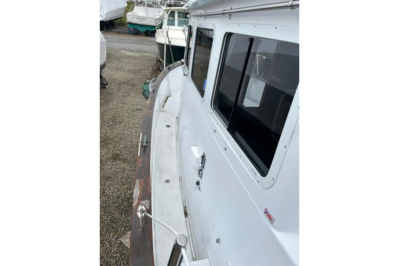 Slide: The Image of 1973 Willard 30 boat on land, showing side view with windows and deck details. - 33