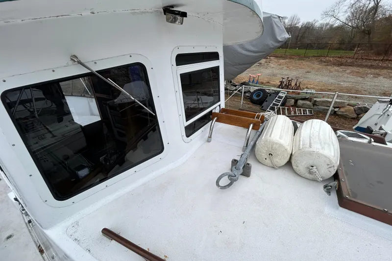 Slide: The Image of 1973 Willard 30 boat deck with windows, anchor, and fenders in a yard setting. - 34