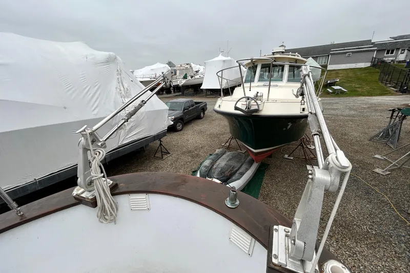 Slide: The Image of 1973 Willard 30 boat in storage yard, surrounded by covered vessels and equipment. - 41