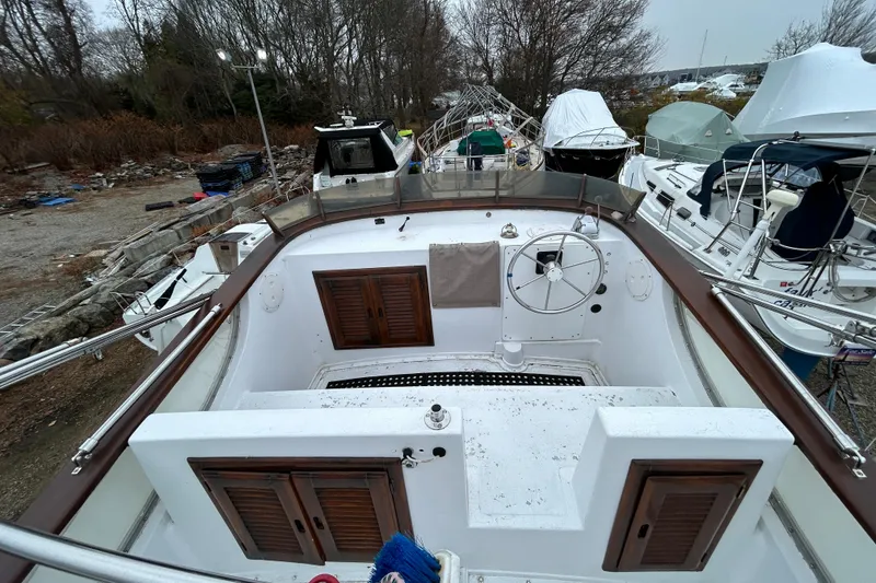 Slide: The Image of 1973 Willard 30 boat cockpit with steering wheel, docked among other vessels. - 44