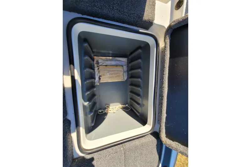 Slide: The Image of 2024 Triton 179 TrX storage compartment with rope and wooden block inside. - 15
