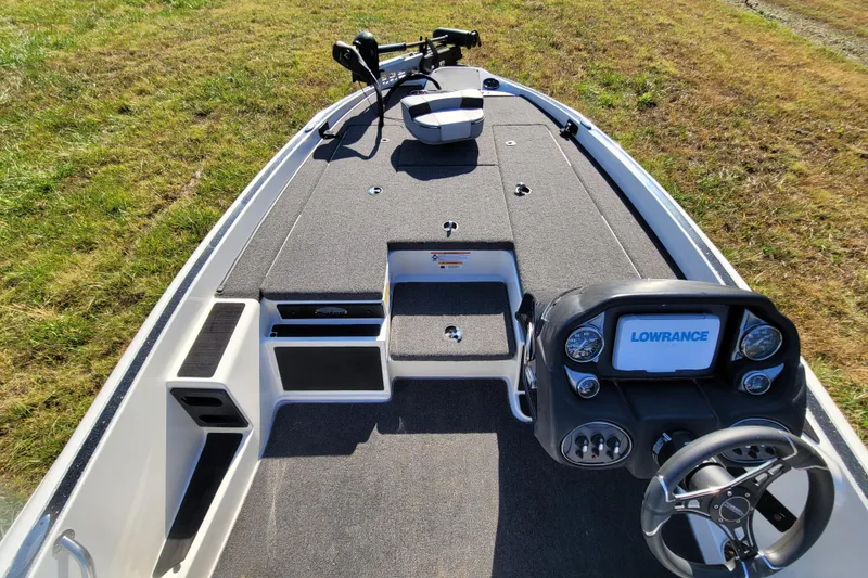 Slide: The Image of 2024 Triton 179 TrX boat interior with Lowrance electronics and steering wheel on grassy background. - 6