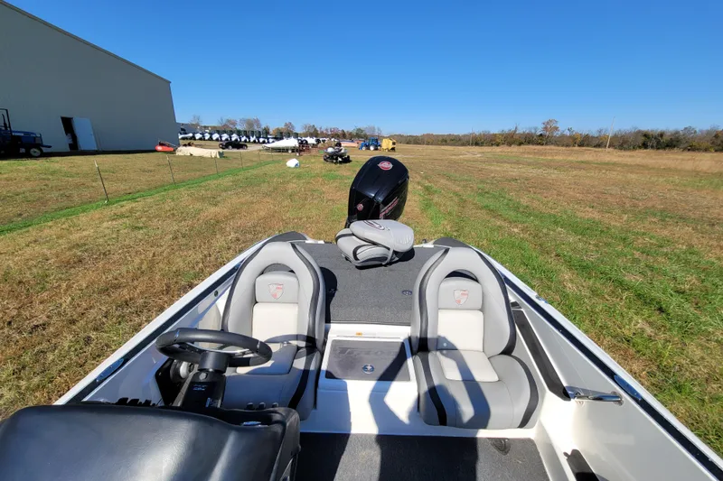 Slide: The Image of 2024 Triton 179 TrX boat interior with dual seats and steering wheel in a grassy field. - 7