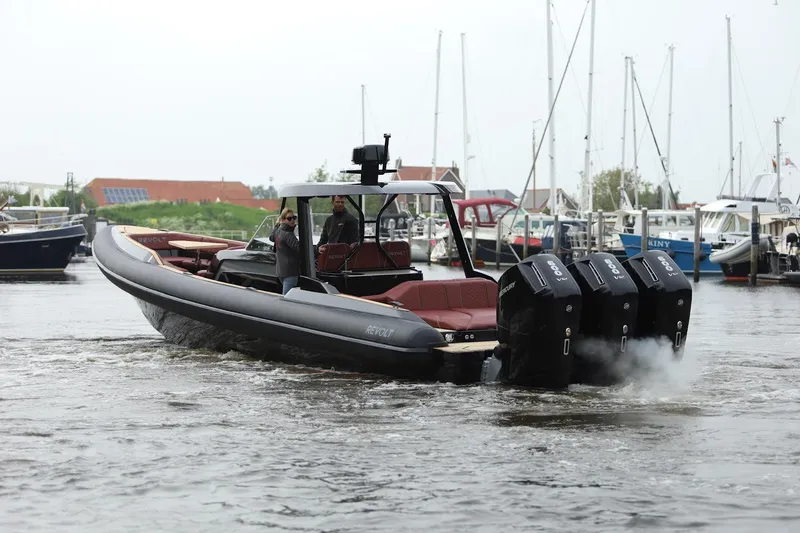 Slide: The Image of 2023 Revolt Comfort 47 boat with triple engines cruising in a marina. - 15
