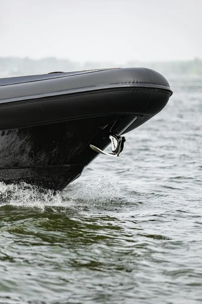 Slide: The Image of 2023 Revolt Comfort 47 boat cruising on water, showcasing sleek black hull design. - 7