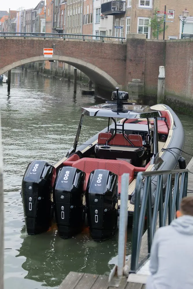 Slide: The Image of 2023 Revolt Comfort 47 boat with triple engines docked near a canal bridge. - 8