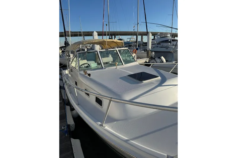 Slide: The Image of 2000 Mainship Pilot 30 boat interior with helm, seating, and canopy at marina. - 10