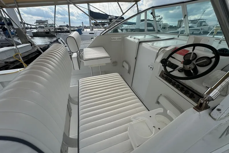 Slide: The Image of 2000 Mainship Pilot 30 boat interior with white seating and steering wheel. - 18