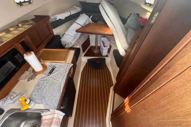 Slide: The Image of Interior of a 2000 Mainship Pilot 30 boat with wooden cabinetry and compact kitchen area. - 21