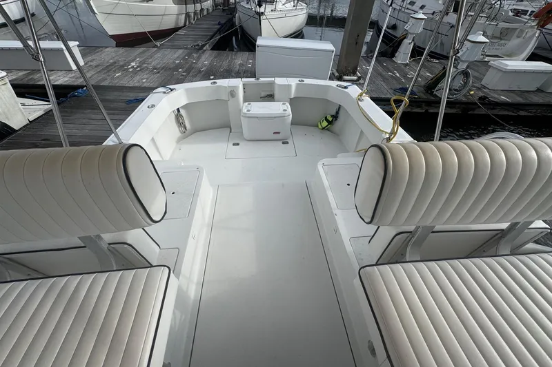 Slide: The Image of 2000 Mainship Pilot 30 boat interior with white cushioned seating at a marina. - 22