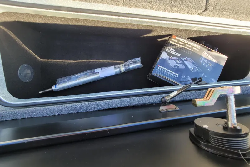 Slide: The Image of 2024 Triton 179 TrX storage compartment with tools and battery charger. - 11