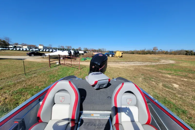Slide: The Image of 2024 Triton 179 TrX boat with red and gray seats in a rural setting. - 6