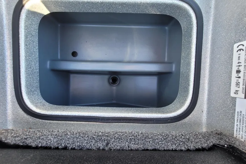 Slide: The Image of 2024 Triton 179 TrX storage compartment with carpeted edge and label details. - 8