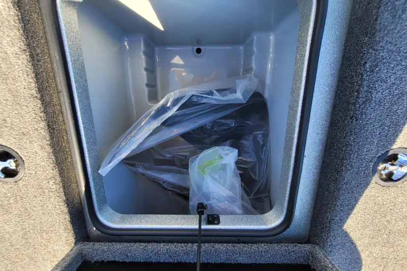 Slide: The Image of 2024 Triton 179 TrX storage compartment with plastic-wrapped items inside. - 9
