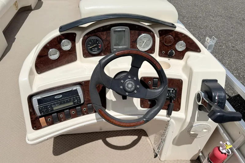 Slide: The Image of 2005 Aqua Patio 240 boat dashboard with steering wheel, gauges, and controls. - 9