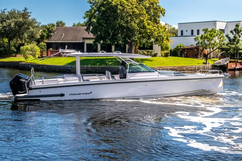 Slide: The Image of 2024 Axopar 37 Sun Top boat cruising on a sunny day near waterfront homes. - 7