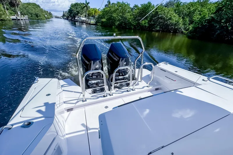 Slide: The Image of 2024 Axopar 37 Sun Top cruising on a scenic waterway with twin Mercury engines. - 9