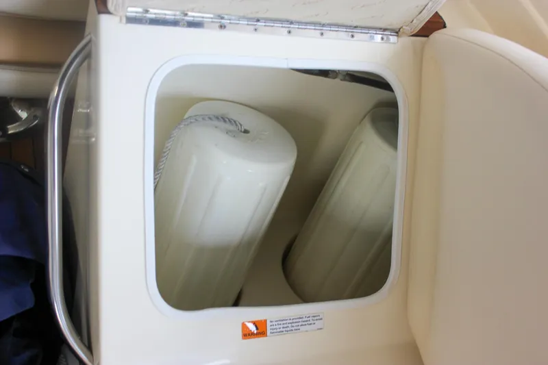 Slide: The Image of 2011 Chris-Craft Corsair 28 boat storage compartment with white fenders on wooden deck. - 18