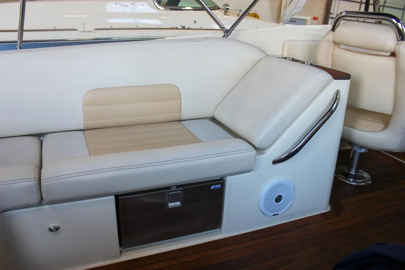 Slide: The Image of 2011 Chris-Craft Corsair 28 boat in showroom, featuring sleek navy hull design. - 50