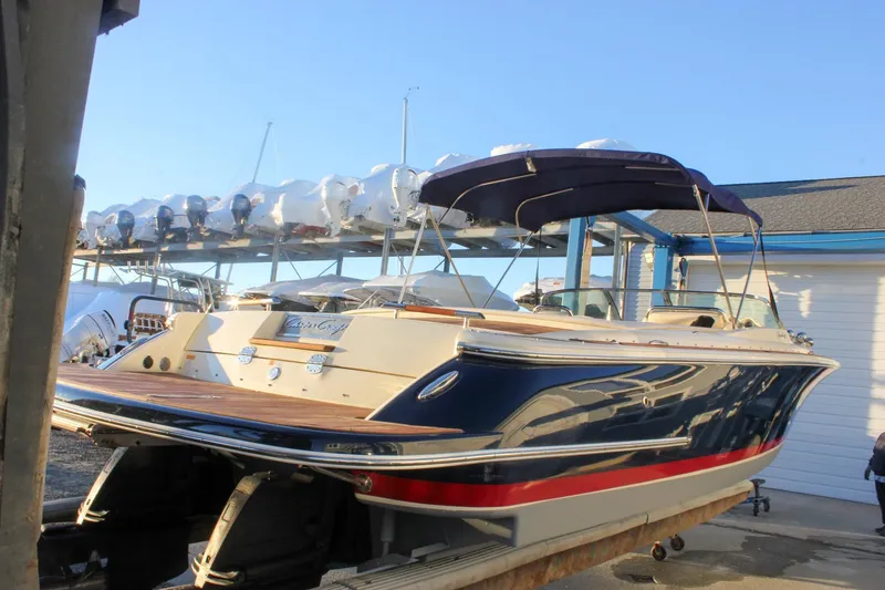 Slide: The Image of 2011 Chris-Craft Corsair 28 boat with navy hull and canopy in a marina setting. - 68