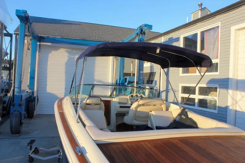 Slide: The Image of 2011 Chris-Craft Corsair 28 boat with canopy, docked near a building. - 76