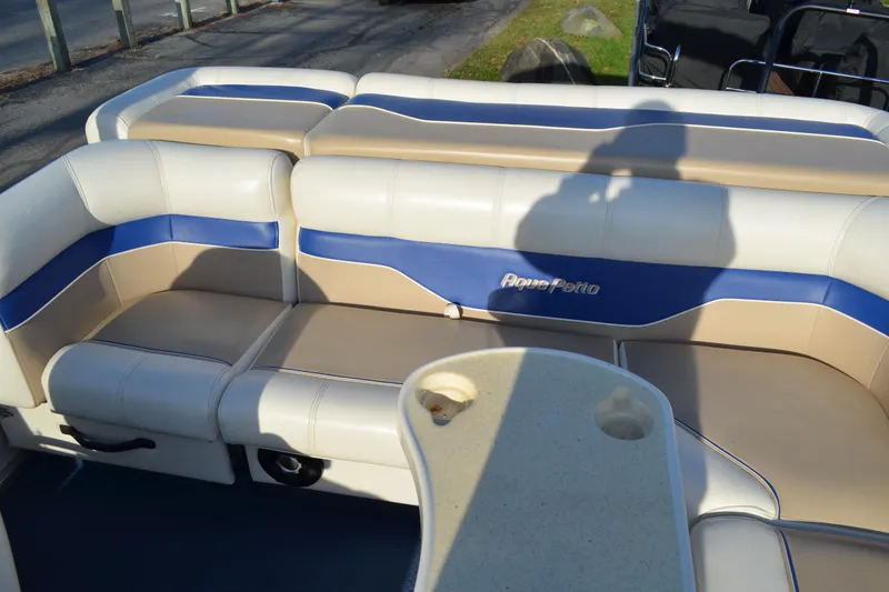 Slide: The Image of 2004 AquaPatio 22 boat interior with beige and blue seating, shadow visible. - 16