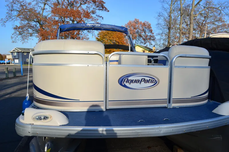 Slide: The Image of 2004 AquaPatio 22 pontoon boat docked, featuring beige and blue design. - 2