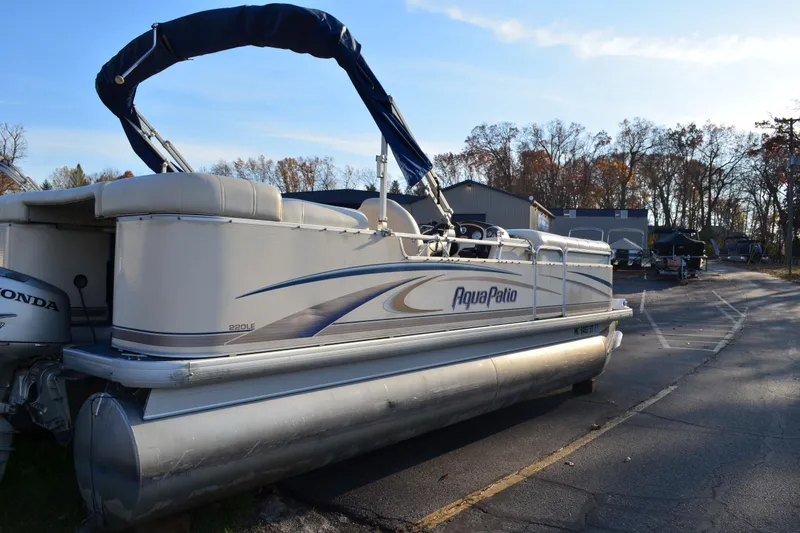 Slide: The Image of 2004 AquaPatio 22 pontoon boat parked on a paved lot with trees in the background. - 4