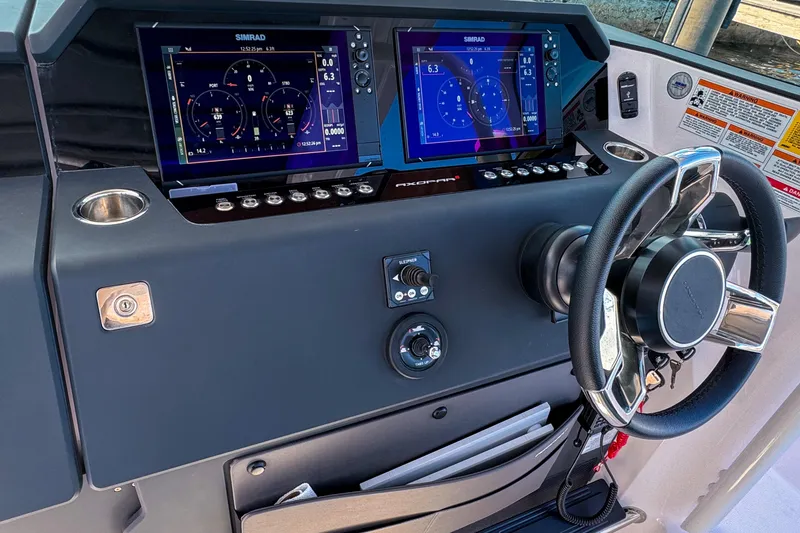 Slide: The Image of 2024 Axopar 37 Sun Top dashboard with dual Simrad displays and steering wheel. - 19