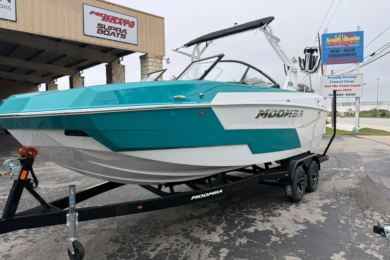 Slide: The Image of 2026 Moomba Max boat in teal and white on a trailer outside a dealership. - 3