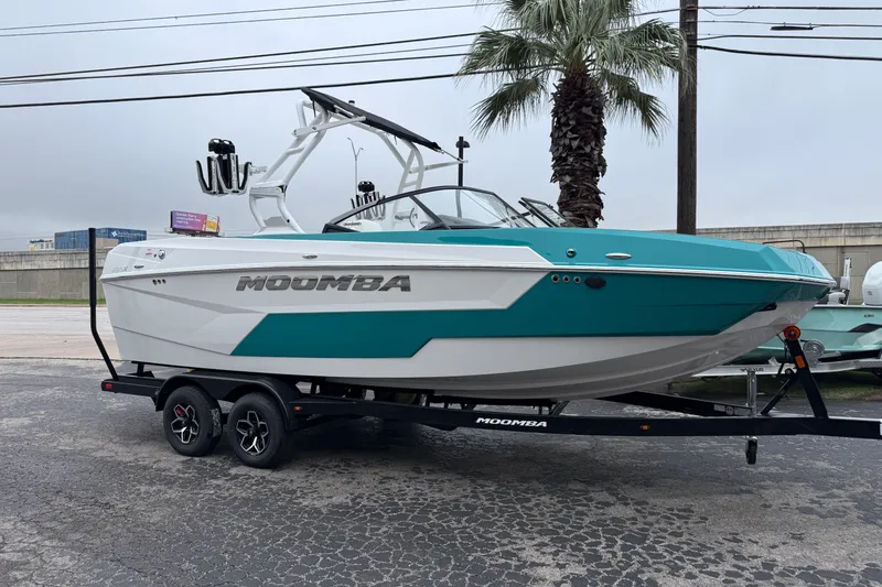 Slide: The Image of 2026 Moomba Max boat in teal and white on a trailer, parked outdoors. - 34