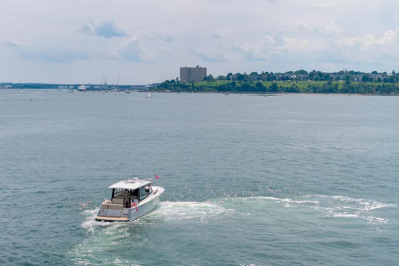 Slide: The Image of 2025 MJM 42 boat cruising on a calm sea with a scenic coastal backdrop. - 10