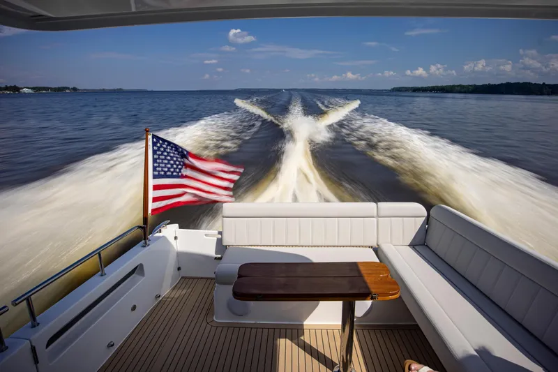 Slide: The Image of A 2025 MJM 42 yacht cruising with American flag, leaving a wake on the water. - 12