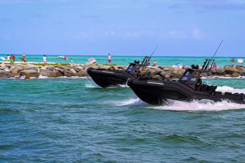 Slide: The Image of Two DGS 777 military boats speeding near a rocky shoreline, 2022 model. - 3