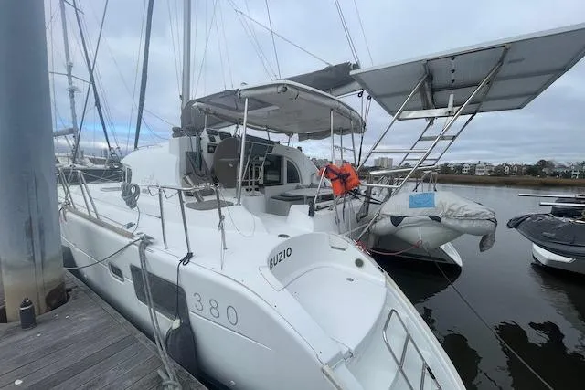 Slide: The Image of 2014 Lagoon 380 S2 catamaran docked at marina, clear sky, calm water. - 2