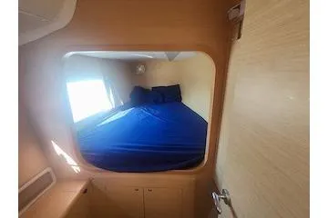 Slide: The Image of 2014 Lagoon 380 S2 cabin interior with blue bedding and wooden finish. - 53