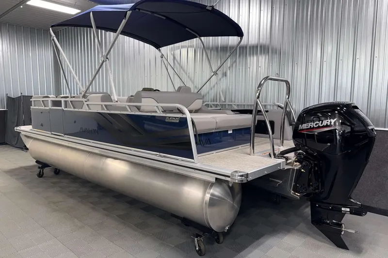 Slide: The Image of 2026 Avalon Venture 2185 VRB pontoon boat with Mercury outboard in a metal-walled showroom. - 8