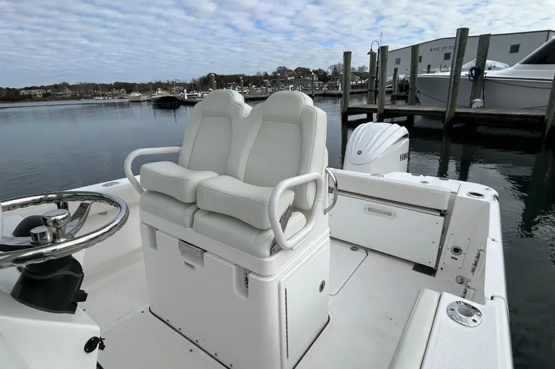 Slide: The Image of 2023 Everglades 235 Center Console boat with dual seats and steering wheel, docked at marina. - 11