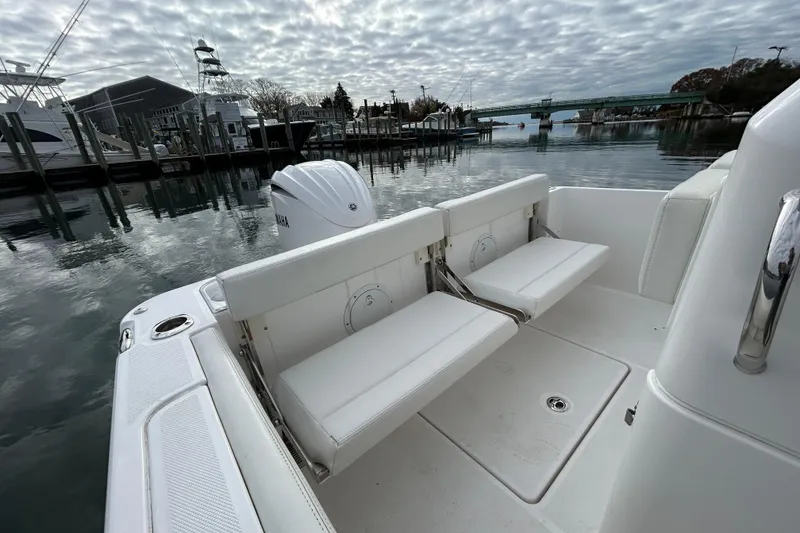 Slide: The Image of 2023 Everglades 235 Center Console boat with white seating, docked by the water. - 19