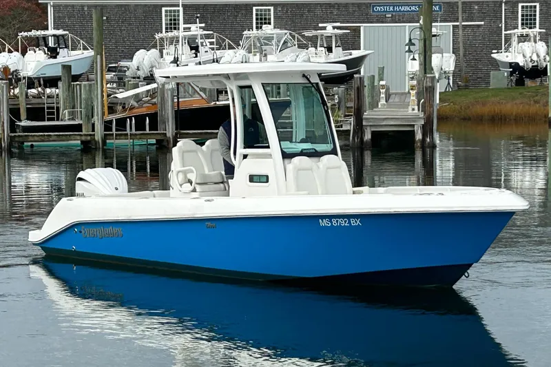Slide: The Image of 2023 Everglades 235 Center Console boat docked in a marina setting. - 2