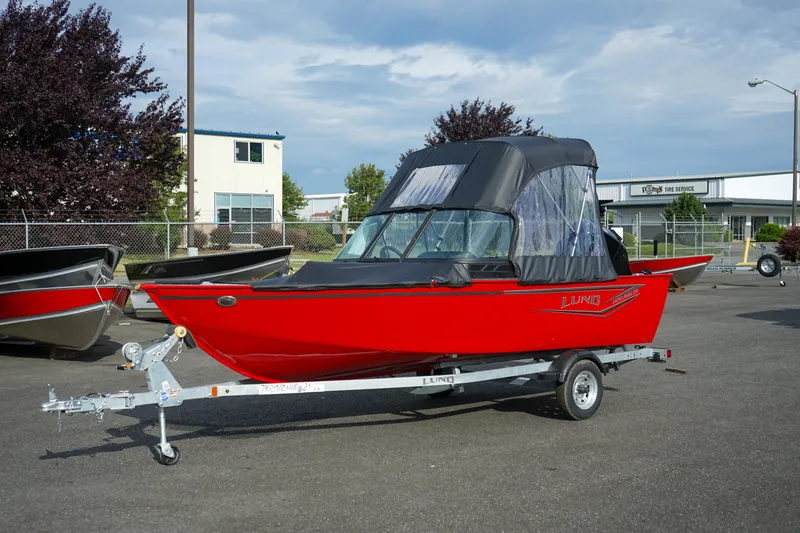 The Image of 2025 Lund 1650 Angler Sport boat in vibrant red on a trailer, parked outdoors. - 0