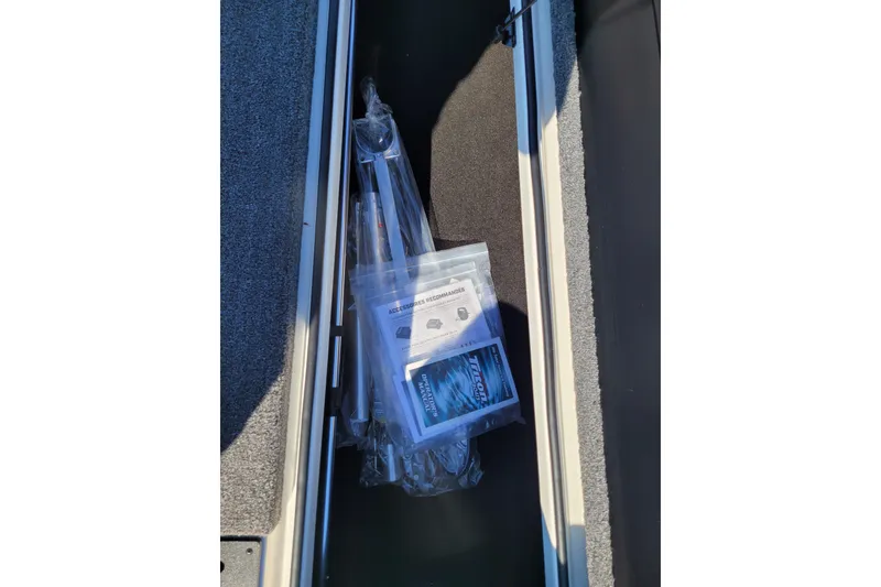 Slide: The Image of Storage compartment of 2024 Triton 18 TrX boat with accessories and manuals. - 14