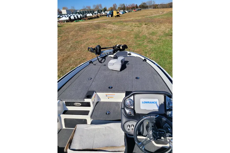 Slide: The Image of 2024 Triton 18 TrX boat interior with Lowrance electronics, parked on grassy field. - 3