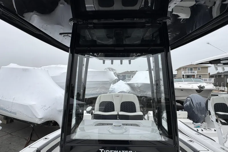 Slide: The Image of 2026 Tidewater 210 CC Adventure boat, docked with covered vessels in the background. - 23