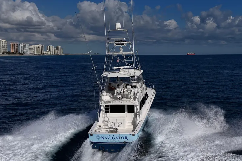 Slide: The Image of 1998 Viking 50 Convertible yacht cruising near city skyline under cloudy sky. - 12